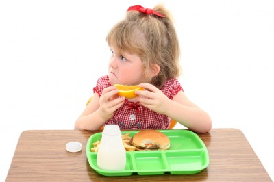 Frowning school girl eats lunch