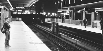 A lone woman waits at a transit stop.