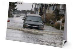 A vehicle makes its way through a flooded street of Milford, Connecticut