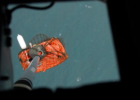 The emergency towing system hangs on a pendant below an Air Station Kodiak MH-60 Jayhawk helicopter.