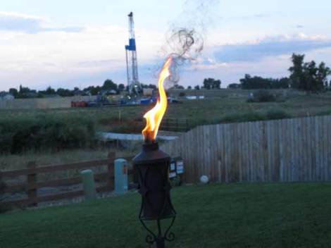 Ironic flame of a tiki torch at a backyard BBQ foreshadowing  events to come.