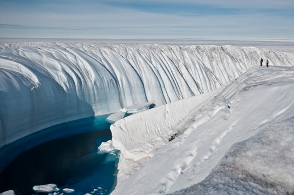 Overflow water from a melt lake carved this canyon in Antarctic ice; note the two people on the right for scale.