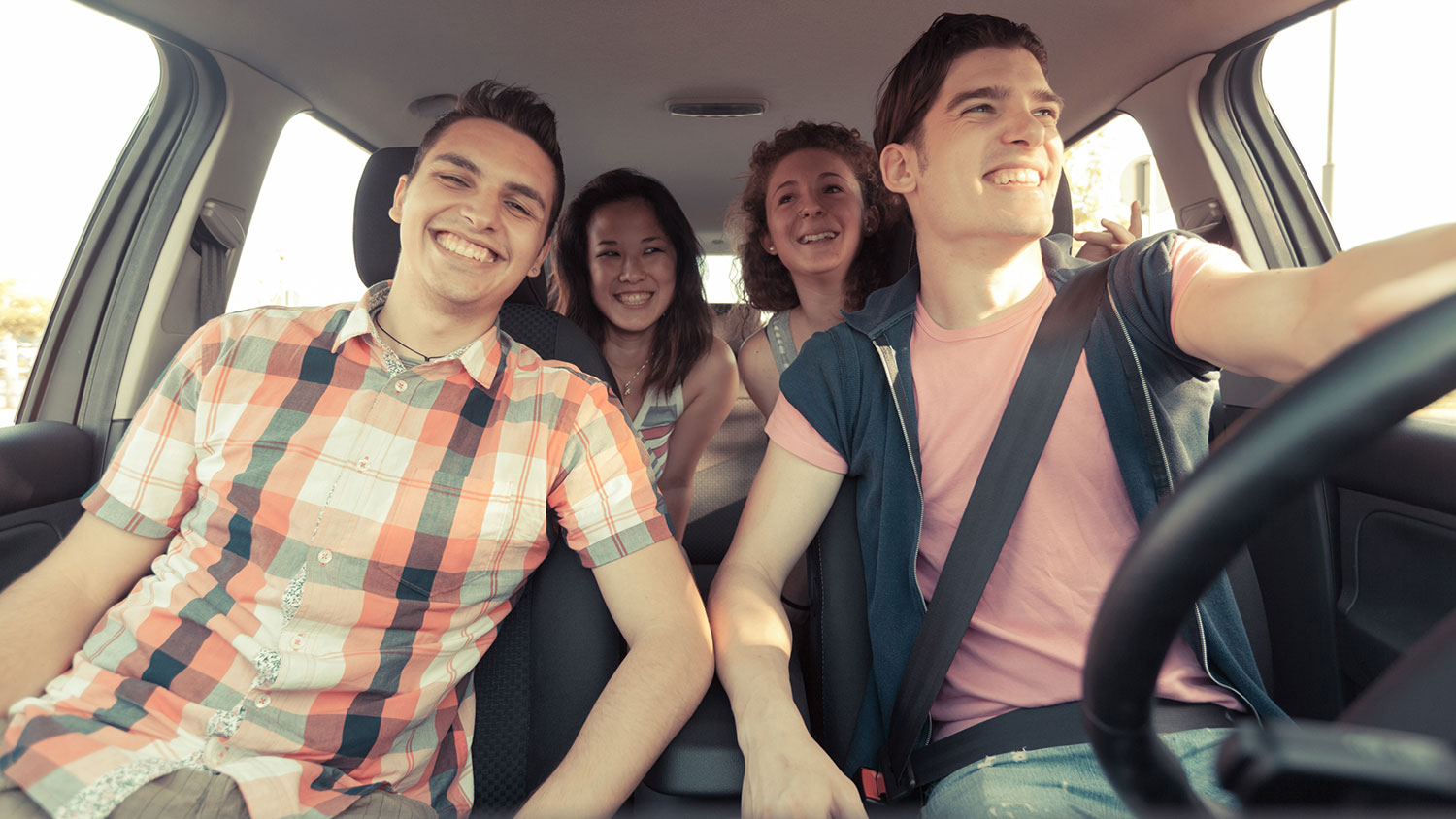 four happy people in car