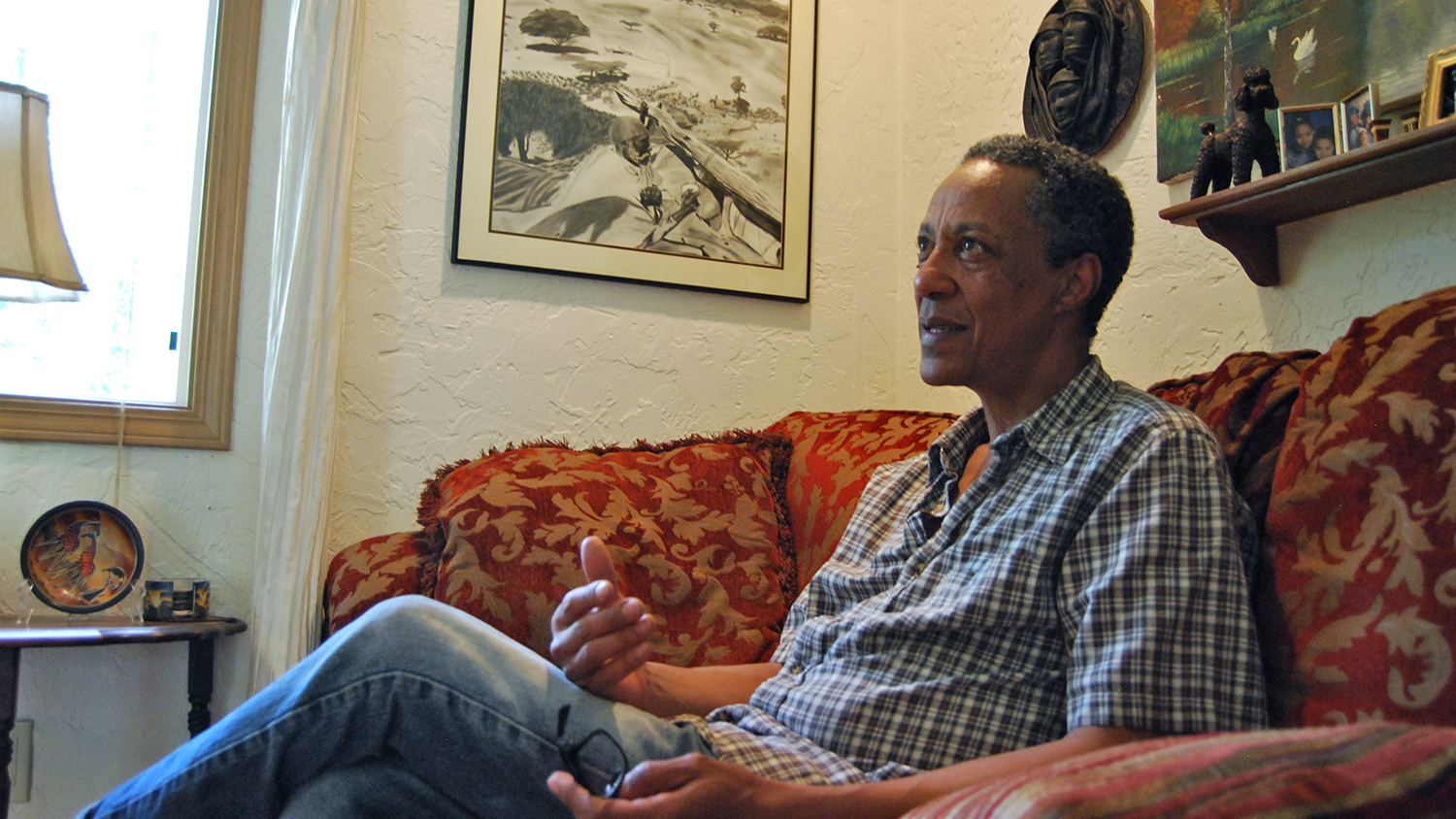 Tekola sits in his home in Maple Valley, Wash., an hour south of Seattle. The drawing on his left is one of his few remaining pieces from his days in Kenya.