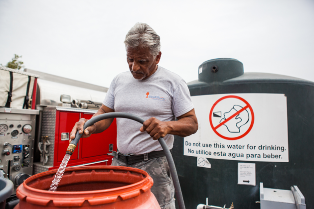 Reuben Perez fills up a barrel of water at the public tank to bring to Juana Garcia's home. The water will be used to do laundry, take bucket showers, and flush the toilet.