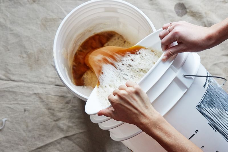 Step 17: Sanitize your 5-gallon pot or bottling bucket and pour the wort back and forth between the two sanitized containers several times, then back into the fermenter.