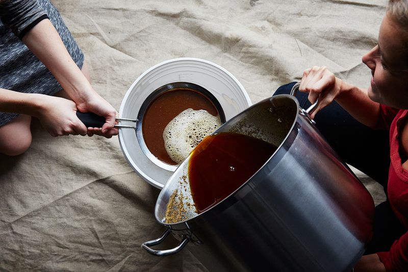 Step 14: Pour your cooled wort through a sanitized strainer into the sanitized fermenter (having a buddy helps for this!). 