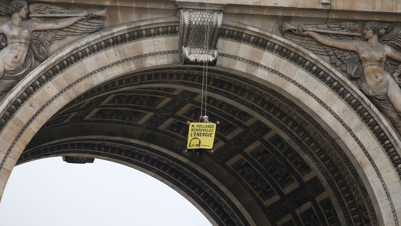 A Greenpeace activist hangs with a banner reading "Mister Hollande, renew energy" from the top of the Arc de Triomphe during a protest on the Champs Elysees avenue in Paris, France, December 11, 2015 as part of the World Climate Change Conference 2015 (COP21).