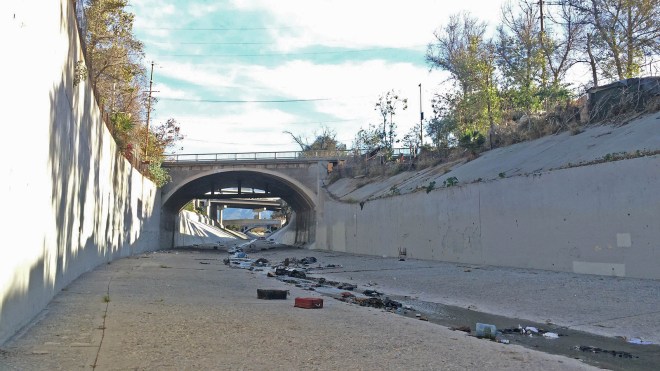 A large encampment dots the top of the top of the banks of the Arroyo Seco in Lincoln Heights, Calif. 