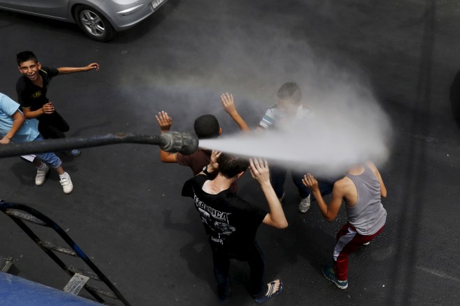 Children react as Greater Amman Municipality personnel spray them with a water sprinkler in order to cool them down as part of measures to ease the effect of a heatwave, in Amman, Jordan, August 3, 2015. REUTERS/Muhammad Hamed - RTX1MV71