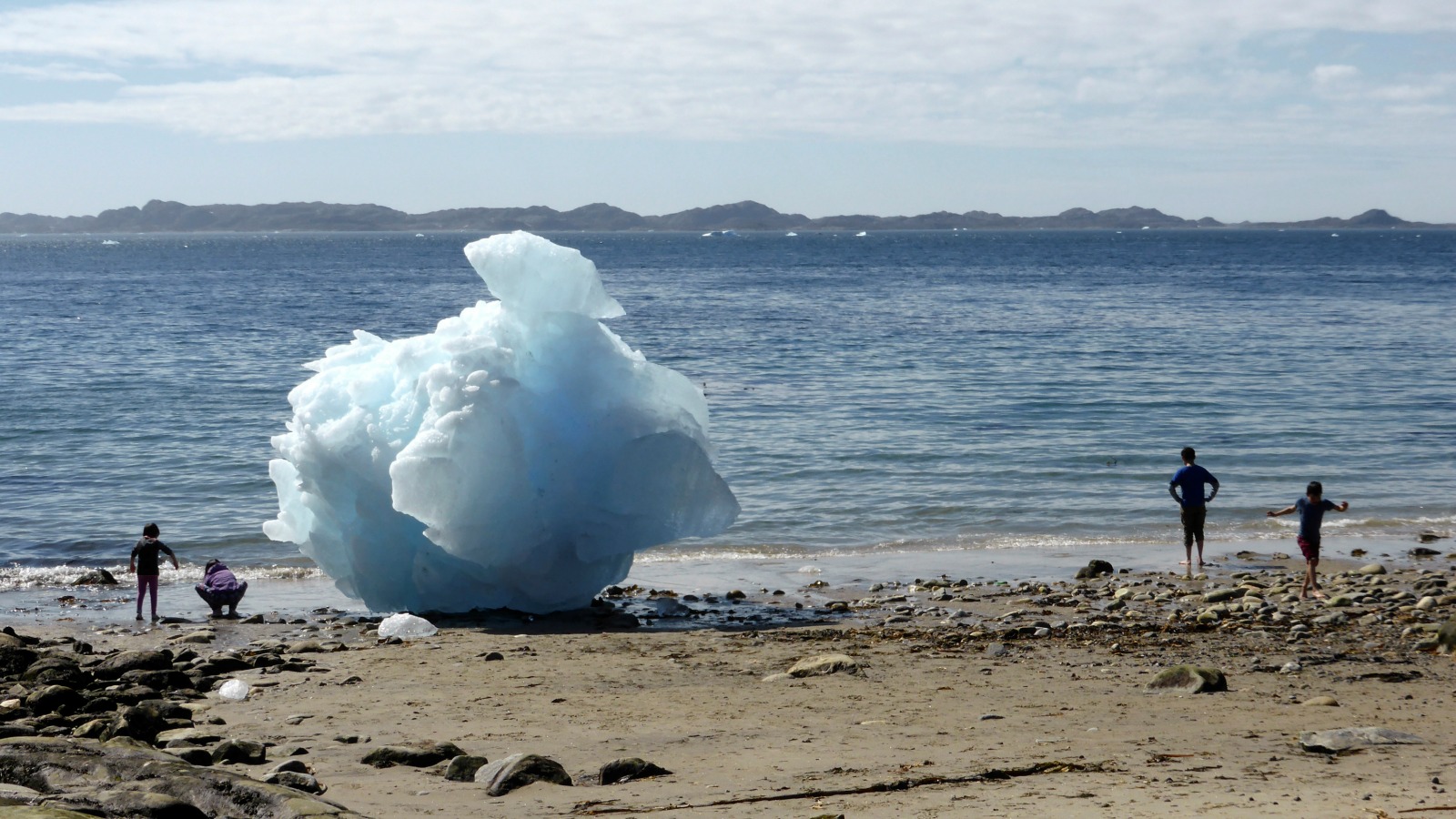 Children play next to icebergs on the beach in Nuuk, Greenland.