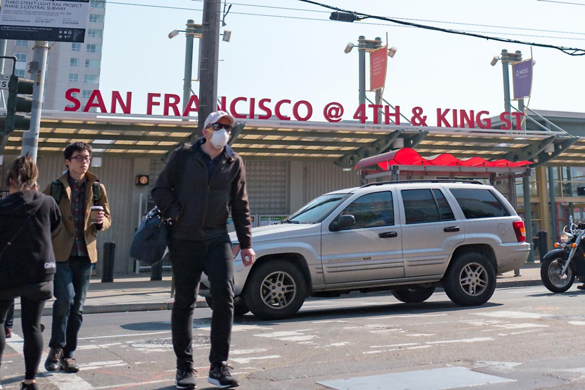 A man wears a surgical face mask while crossing a street in the South of Market (SoMA) neighborhood of San Francisco, California, October 13, 2017.