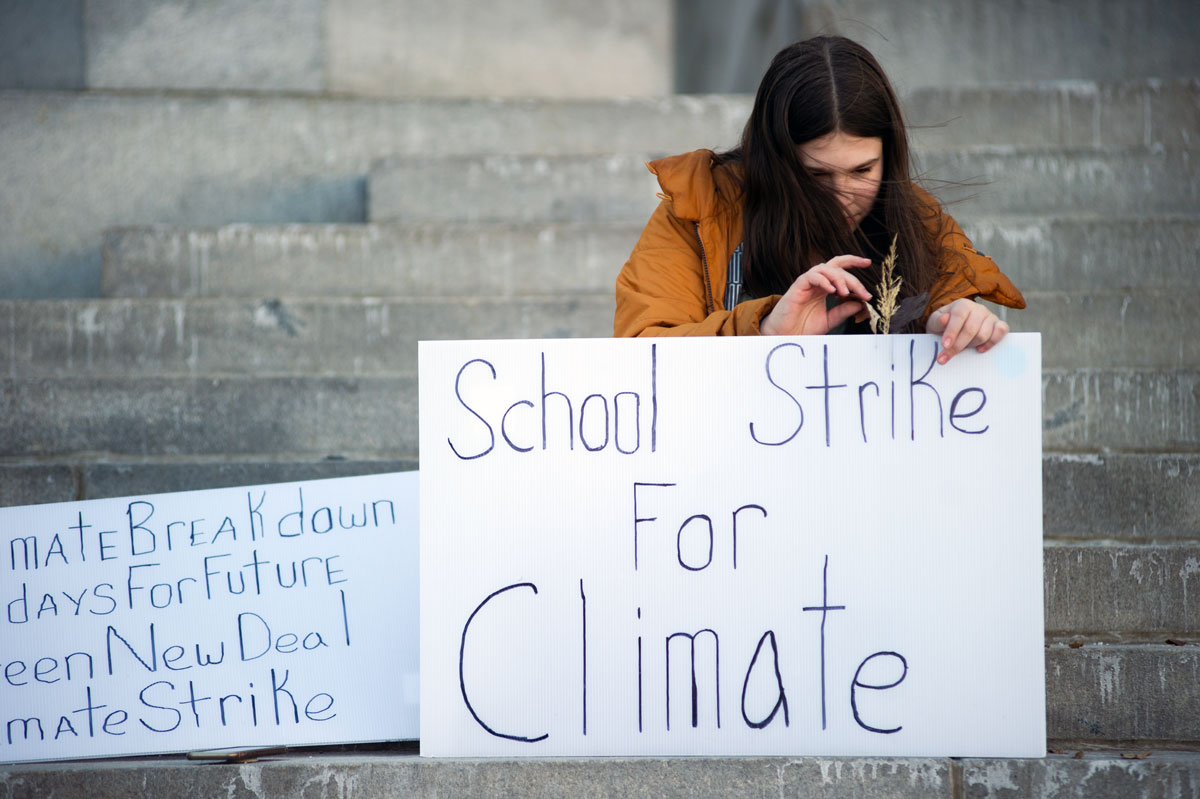 Twelve-year-old climate activist Haven Coleman attaches some leaves to one of her signs while protesting outside Denver City Hall.