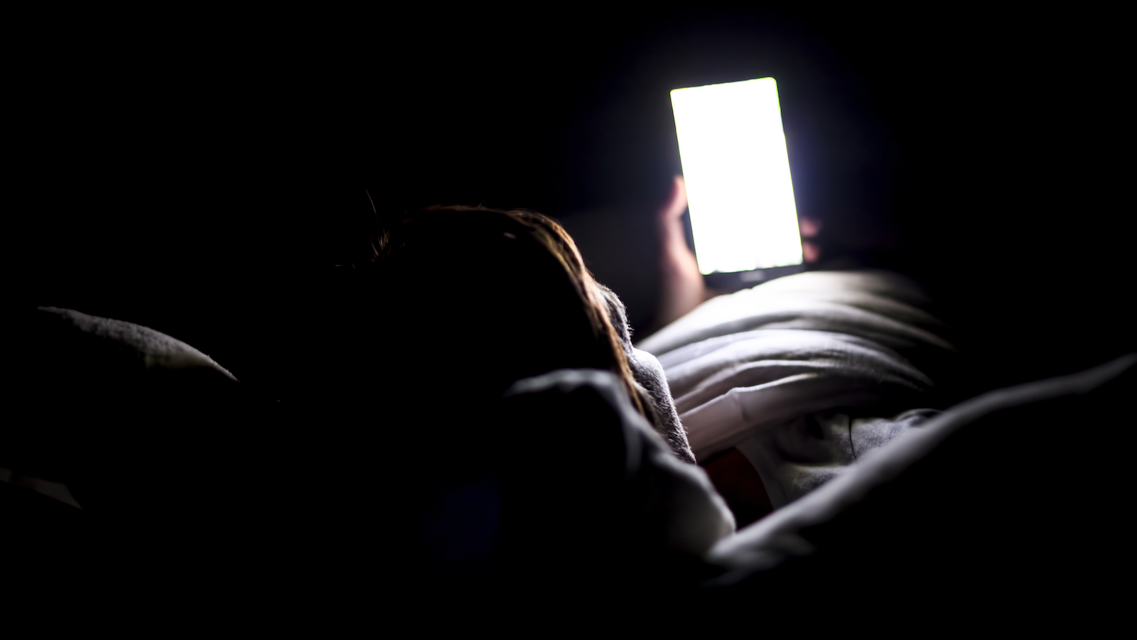 Woman looking up social medial at late night lying in bed, Internet addicted