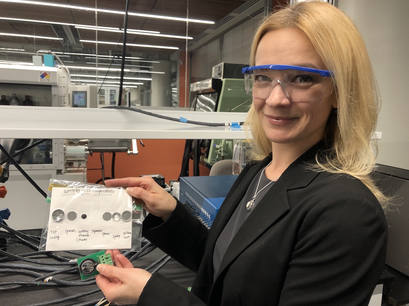 Ekaterina Pomerantseva holding up a card with the different components of a coin battery taped to it