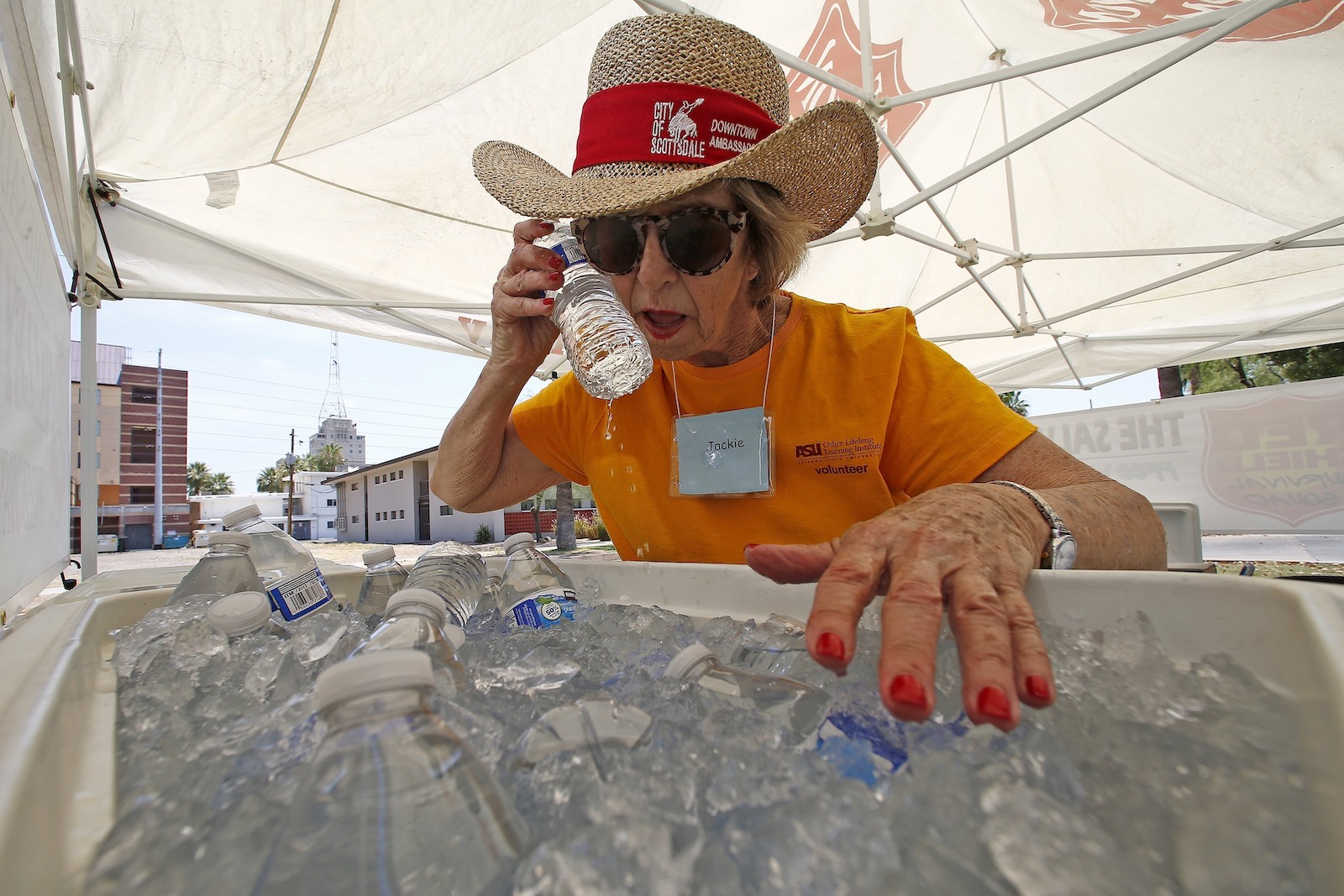 woman holds water bottle to her face during extreme heat wave