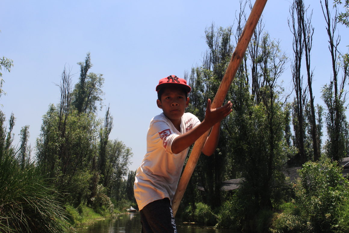 Axel navigates a trajinera on a canal in xochimilco