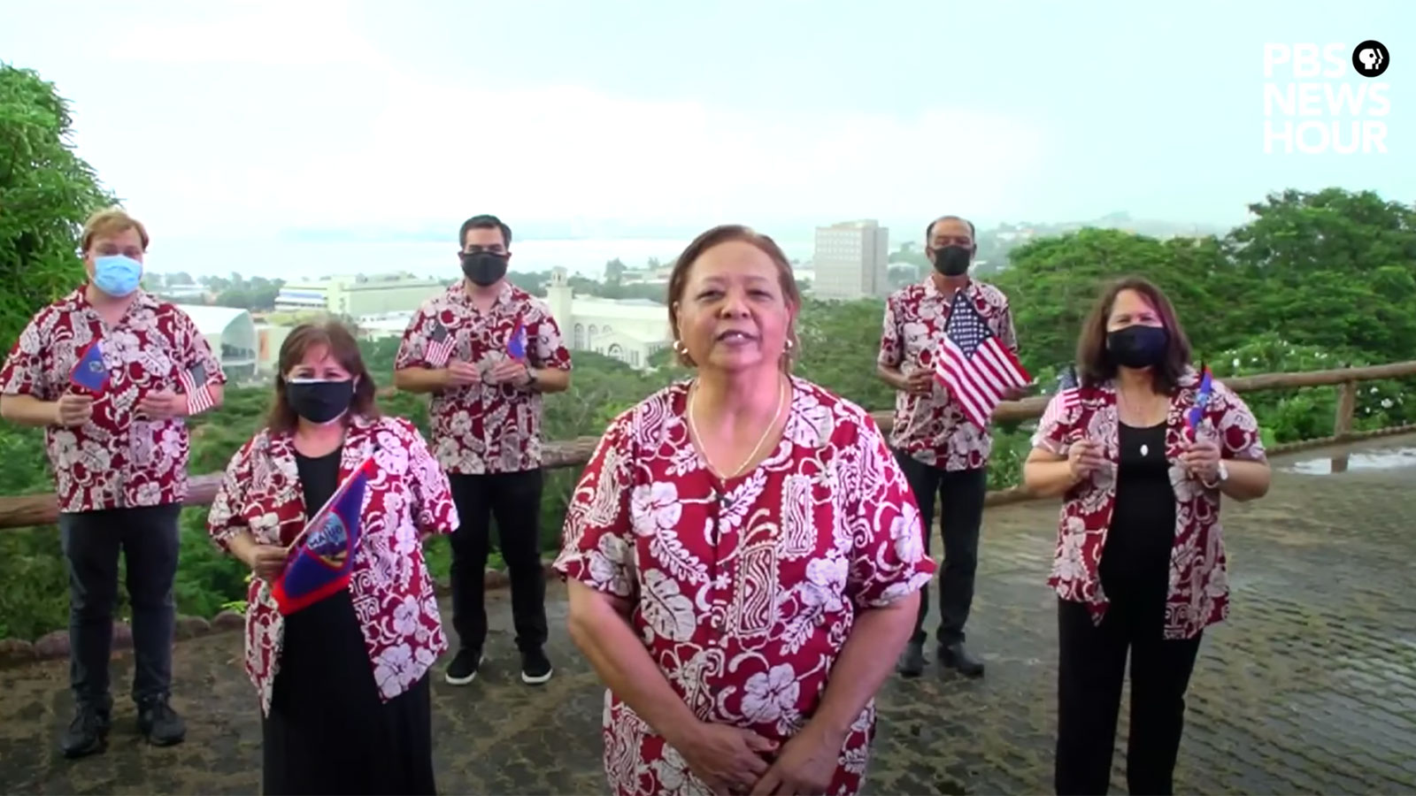 The Guam delegation stands in formation wearing colorful shirts.