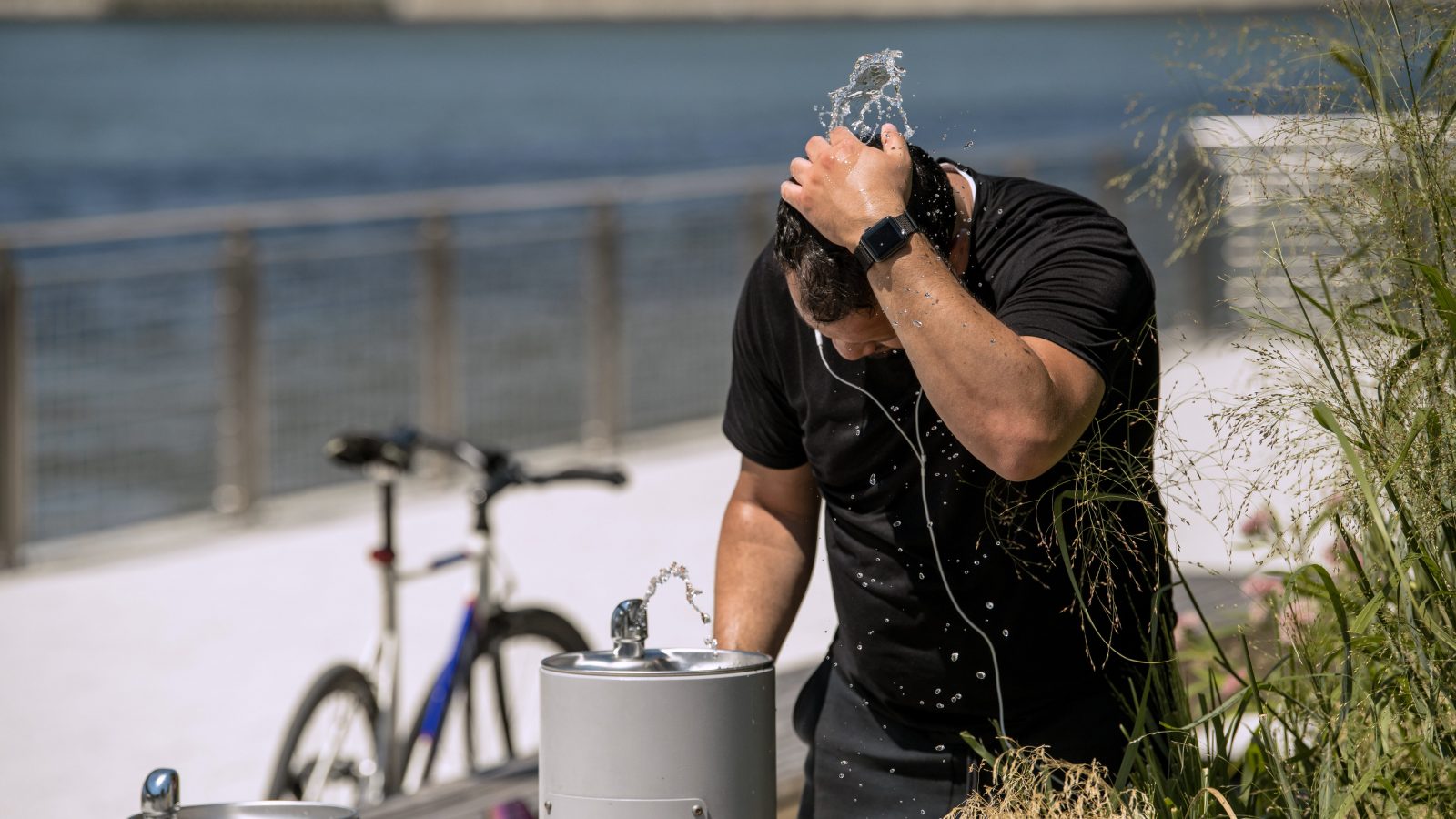 A man stands over a water fountain as a heatwave strikes the northeast of the United States.