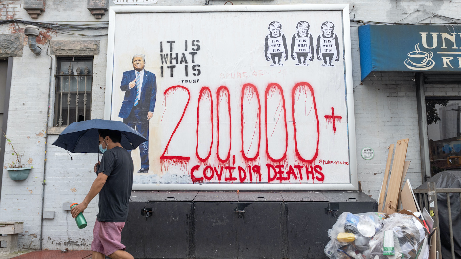 A man walks by graffiti of Trump and lettering reading 