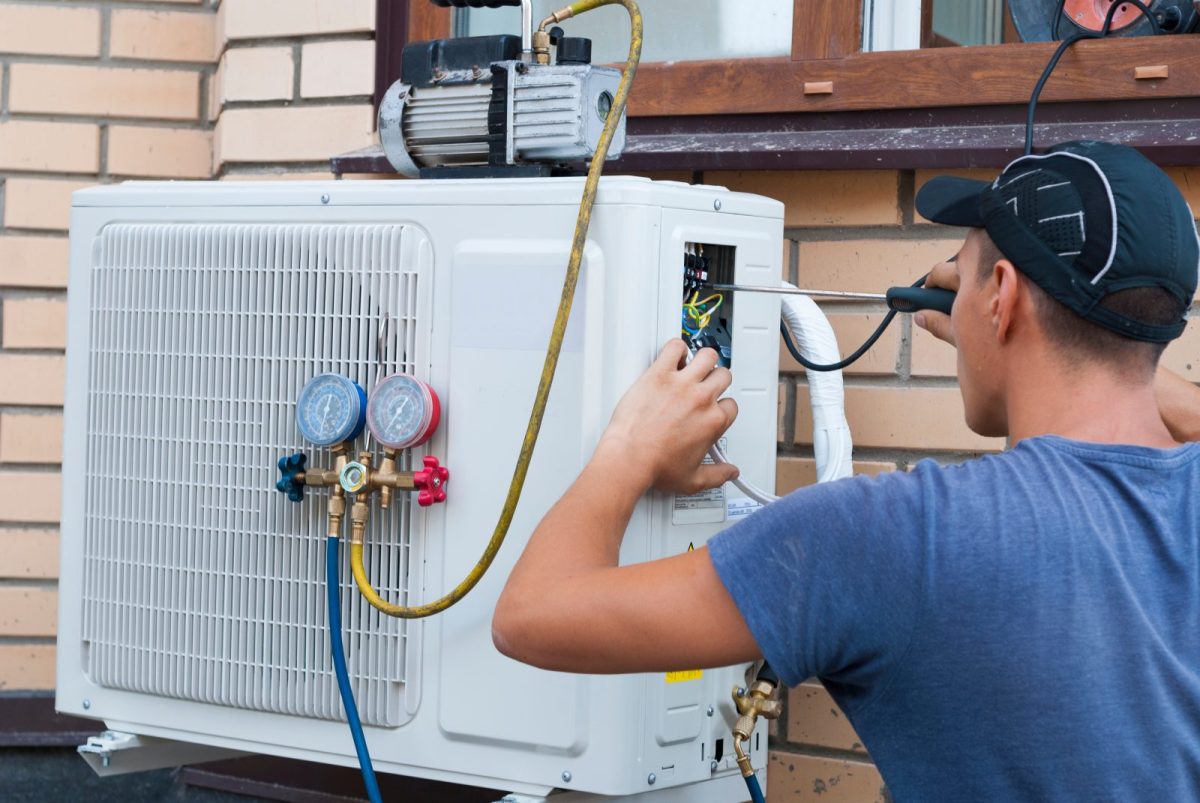 A worker turns a screwdriver to hook hoses to a heatpump