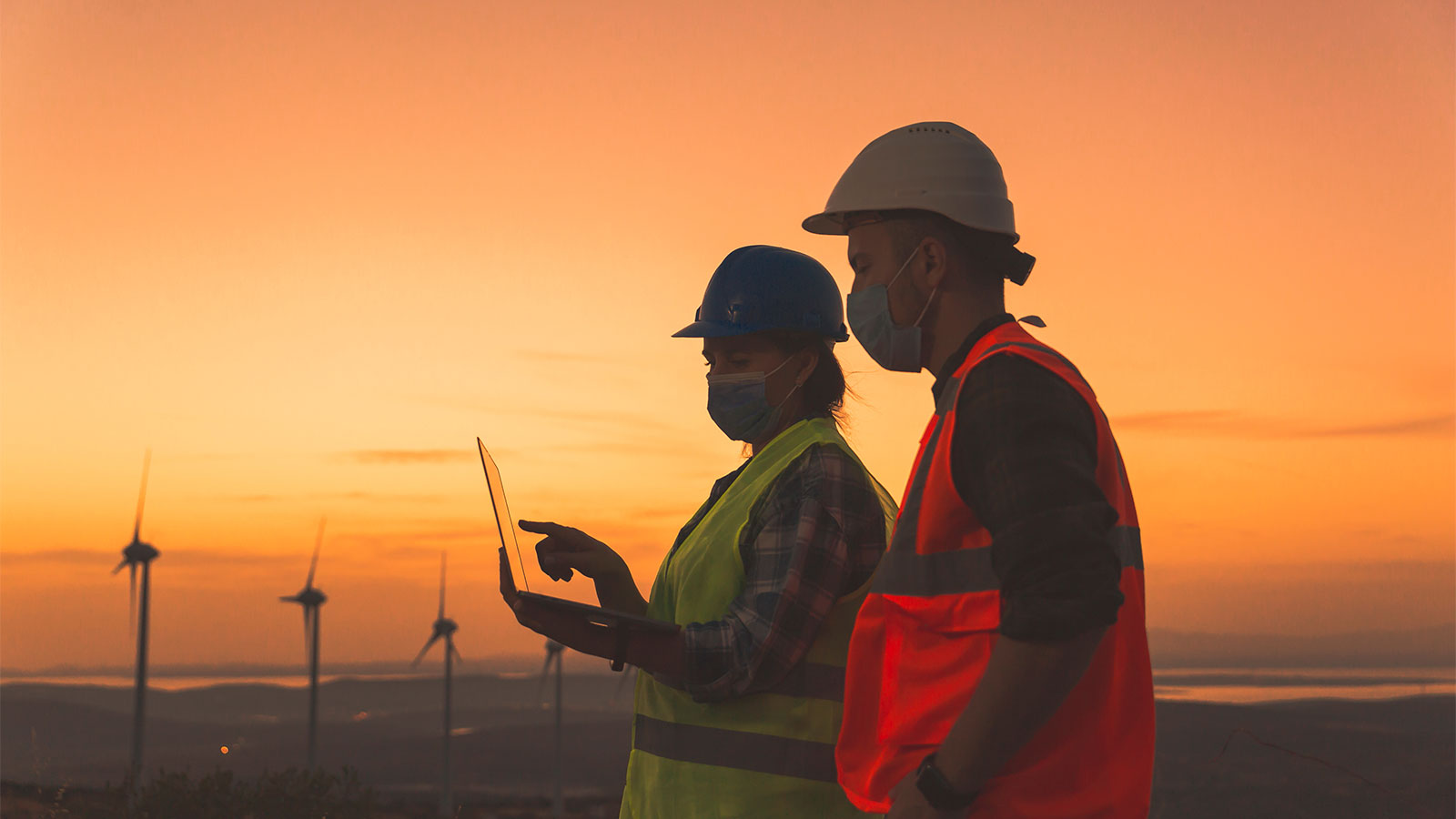 Two engineers doing laptop inspections at a wind turbine field