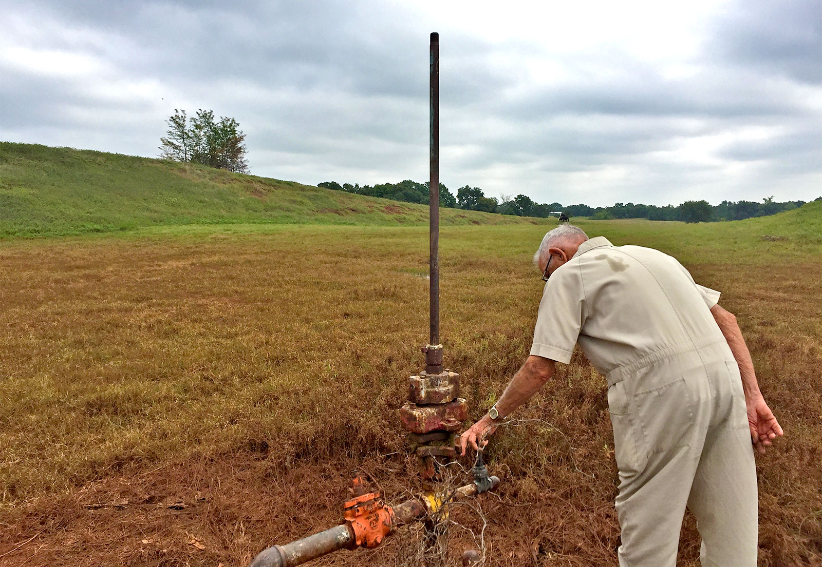 Photo of Troy Lewellen inspecting an abandoned oil well