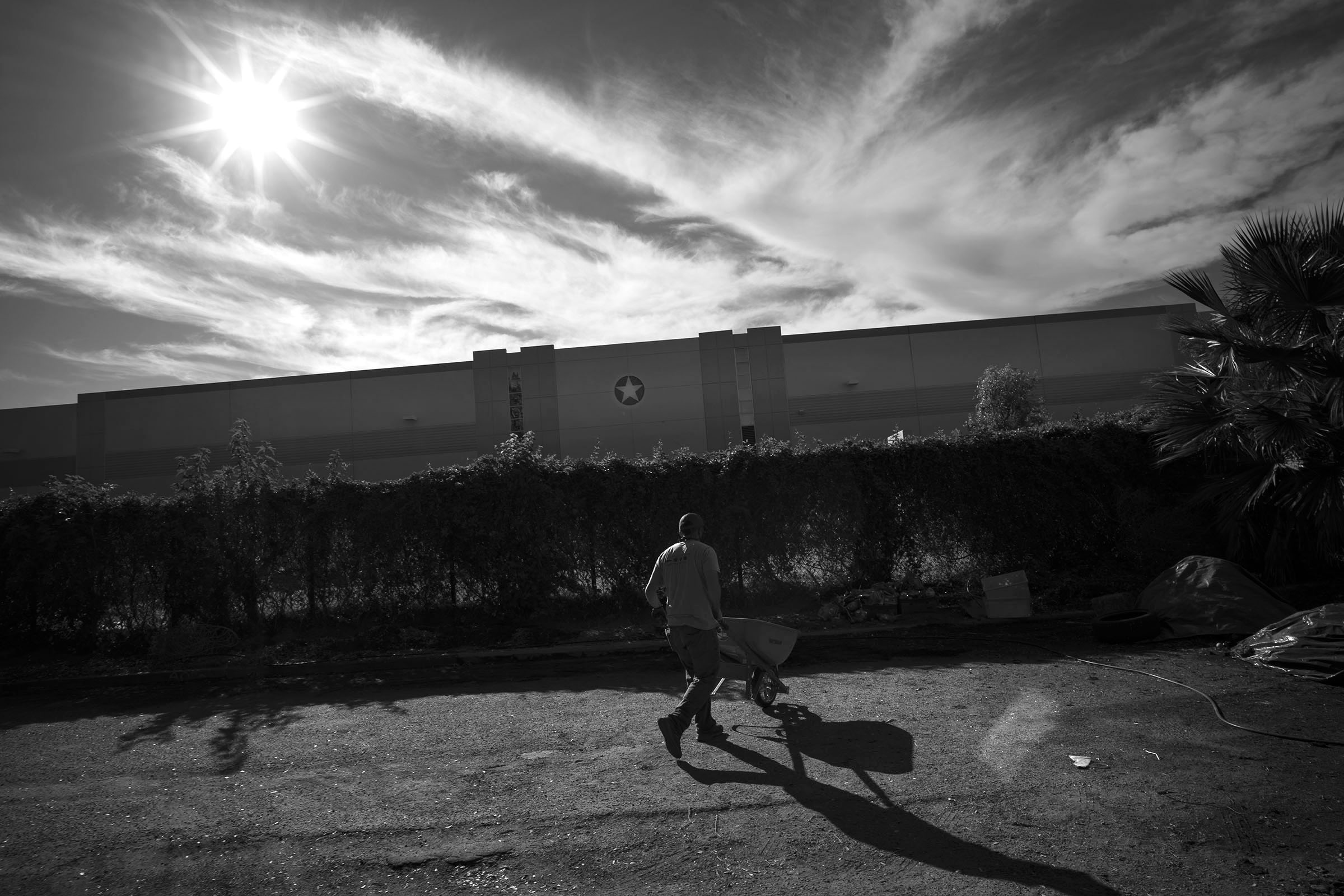 A volunteer moves waste in a wheelbarrow behind an adjoining Hillwood Enterprises commercial building.