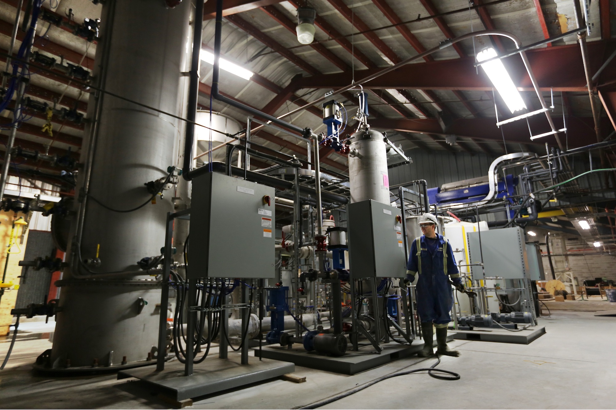 a man stands in front of a big machine that fills an entire industrial space