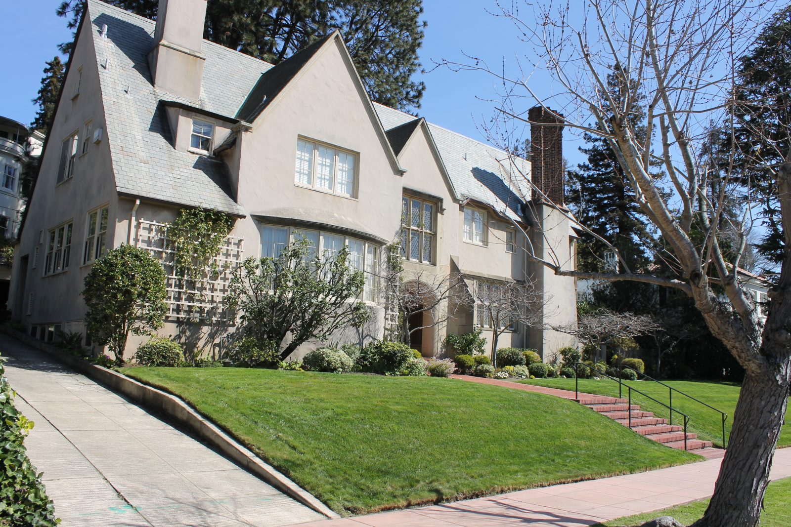 a large, gray mansion with a large green lawn