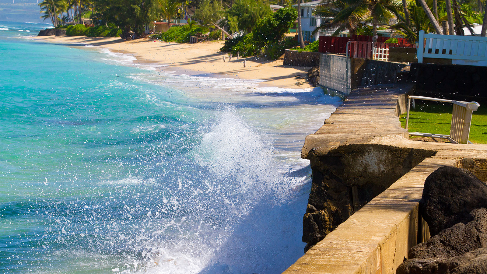 A wave crashing against a seawall in Hawai'i