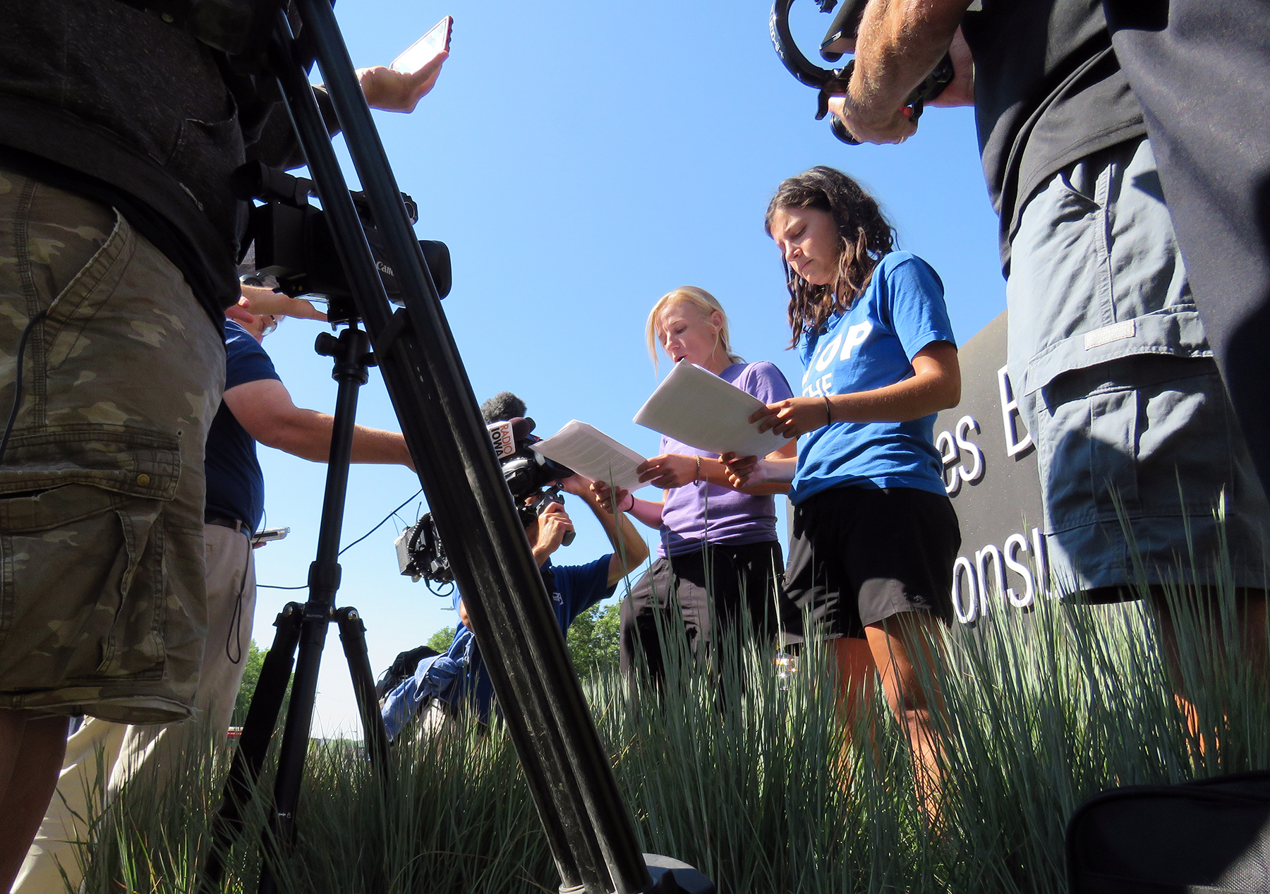 A photo of two women in front of a camera crew reading off of a notecard