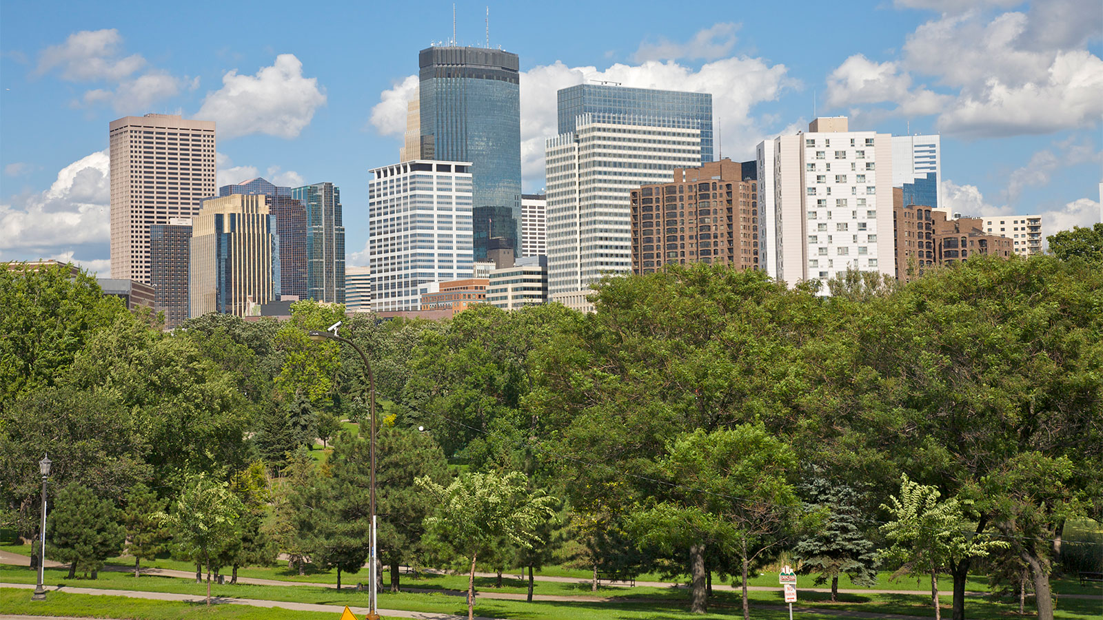 A picture of Minneapolis skyline featuring a park in front of downtown skyscrapers.