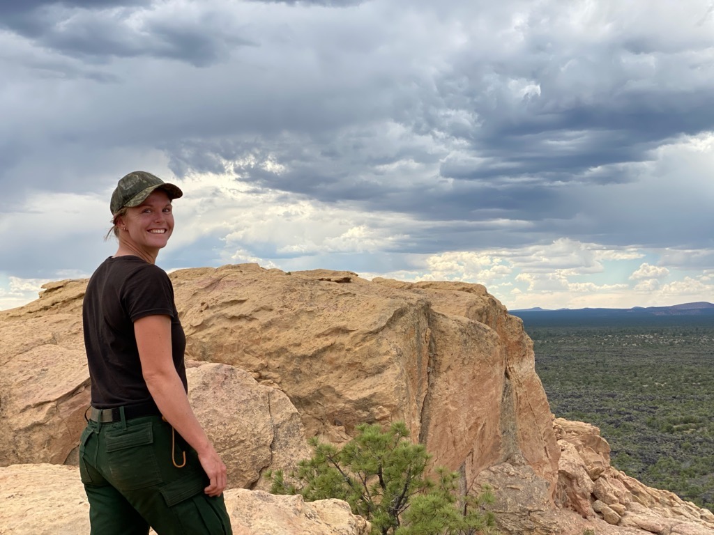 a young woman smiles at the camera in front of a rock formation