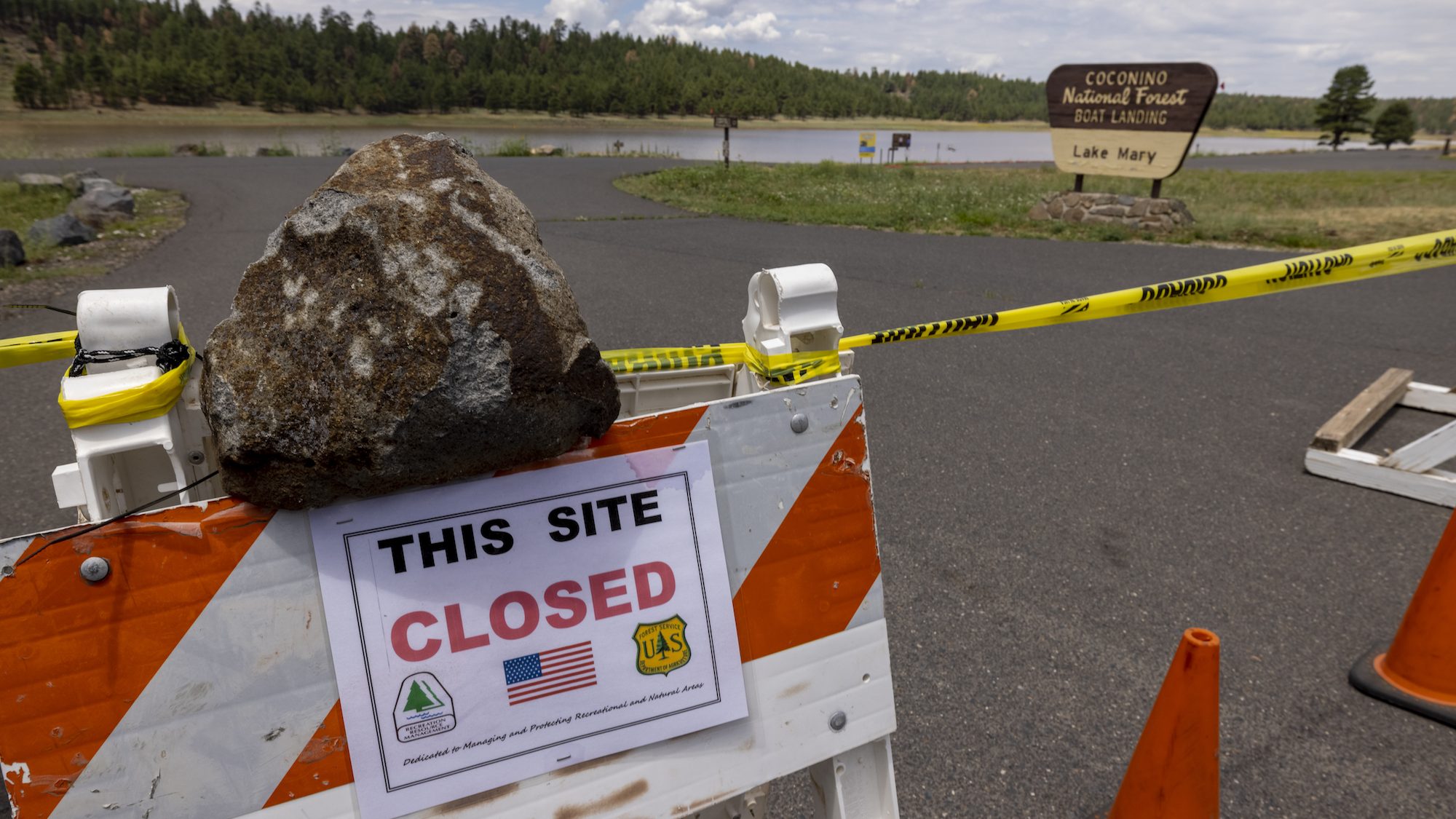 a big rock holds an orange and white sign that says 