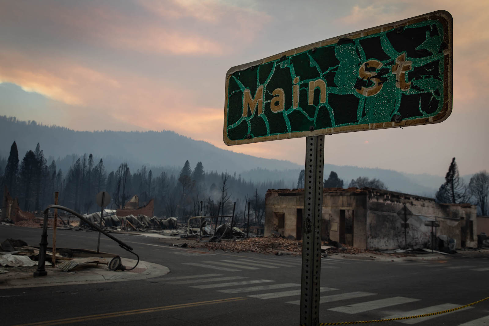 A charred green "main street" sign with a burned mountainous background