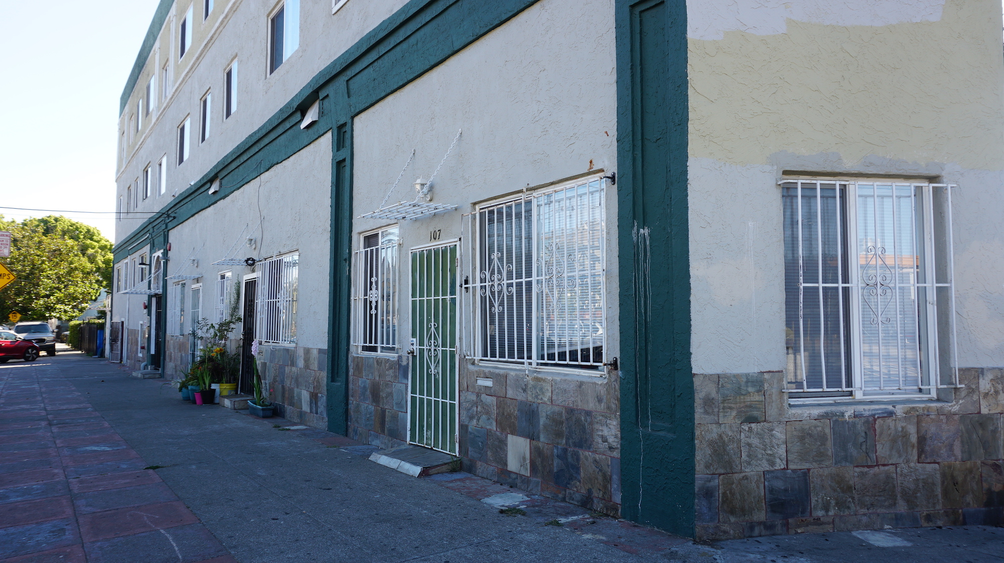 The facade of an older multi-family building, financed by Fannie Mae,with green and tan paint and bars on the windows