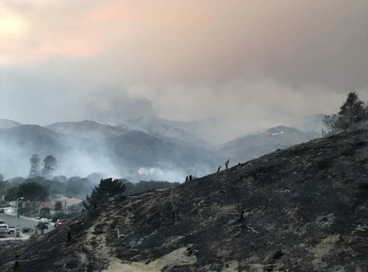 Smoke and dust blow off the burned remnants of Jesse Merrick's family's home after the 2017 Thomas Fire