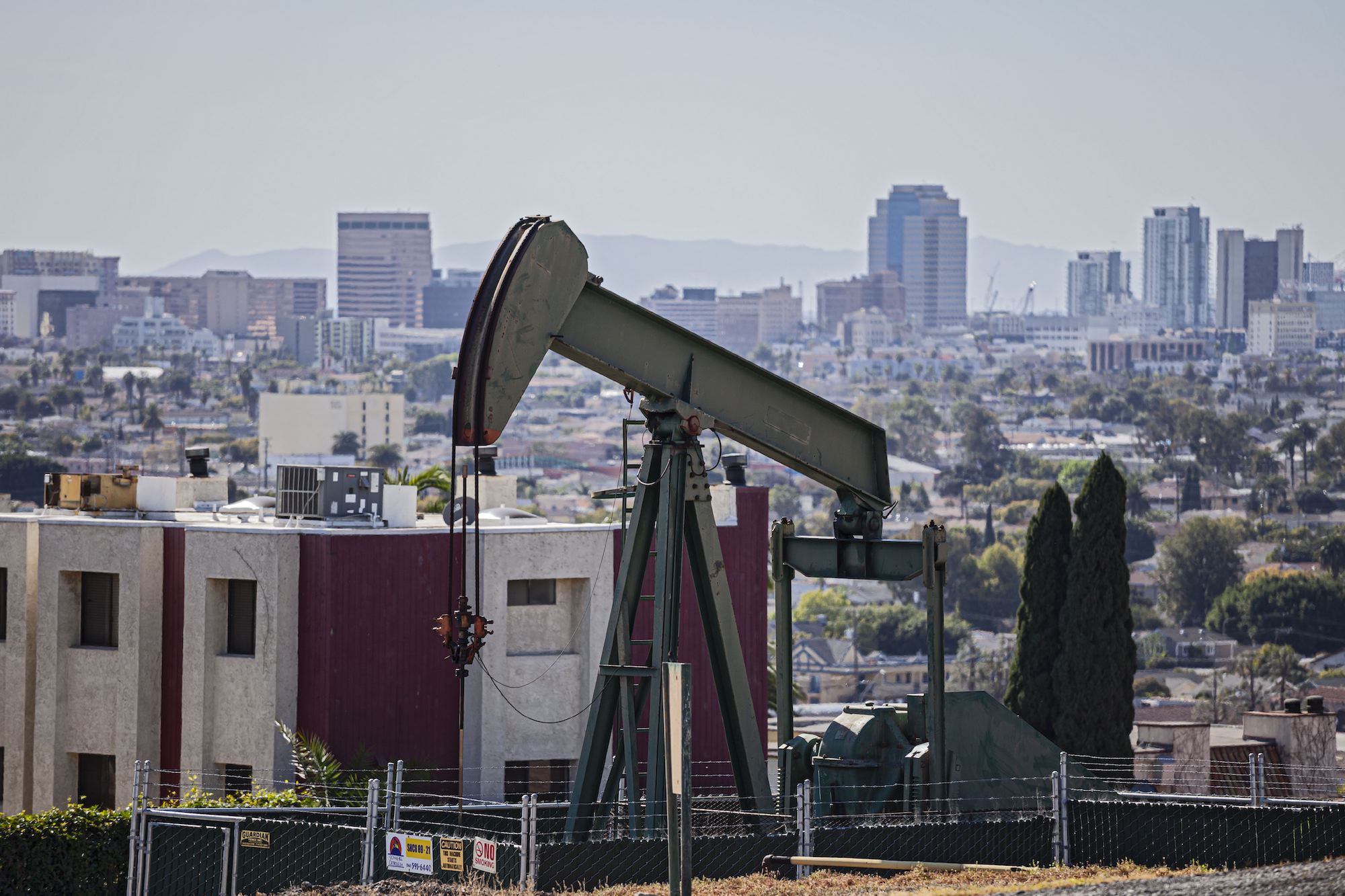 a pumpjack with houses and buildings in the near background