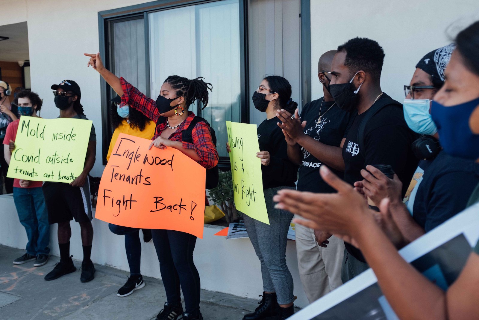 a group of people with signs in front of a house