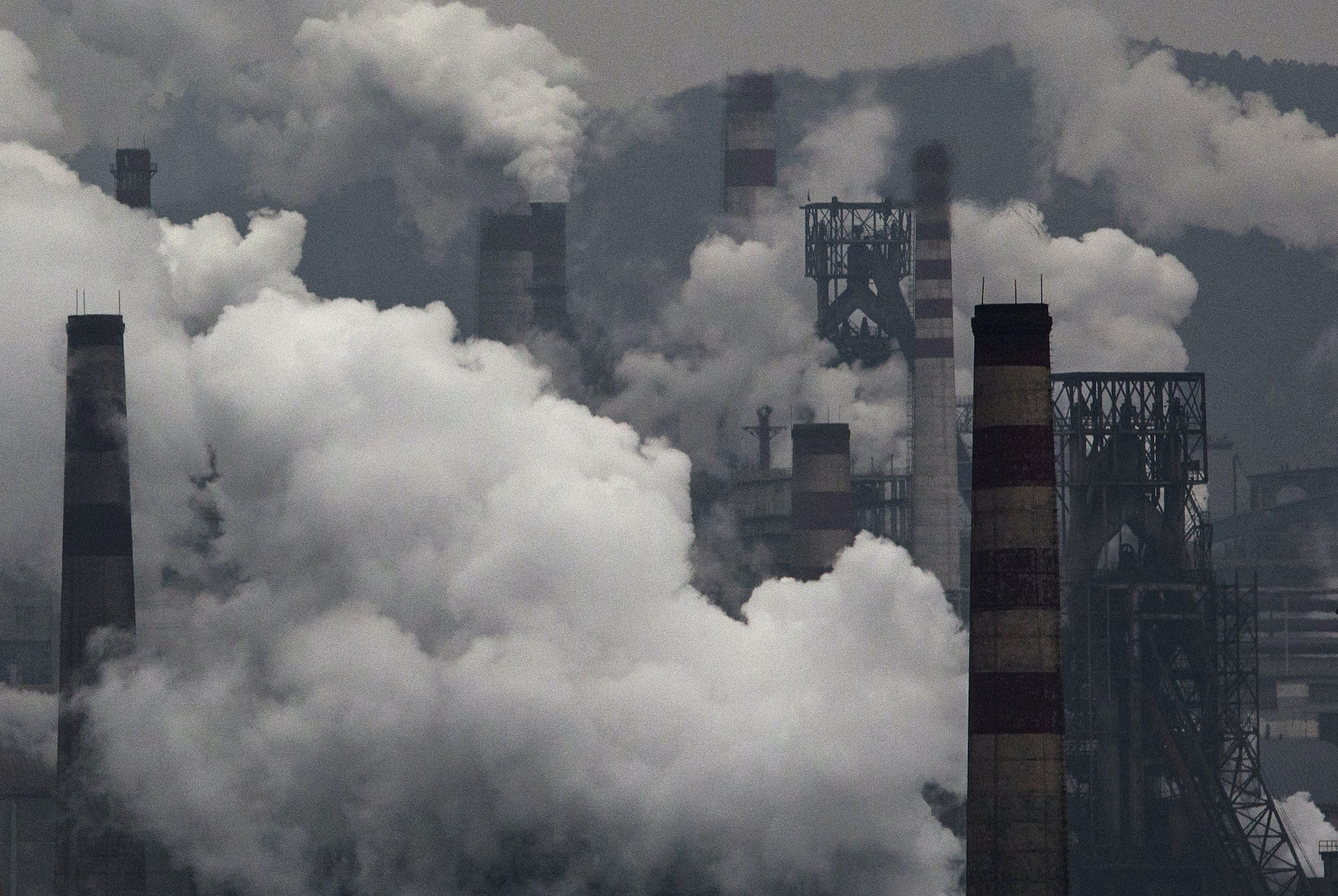 Smoke billows from smokestacks and a coal fired generator at a steel factory.