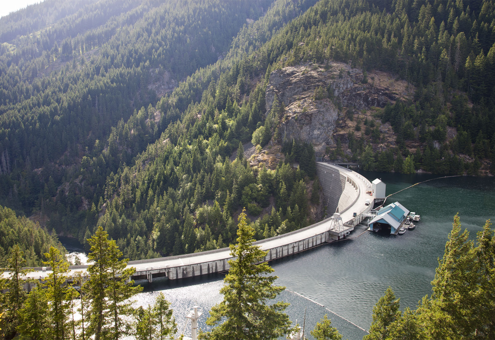 Overhead view of dam with pine trees on mountains in background