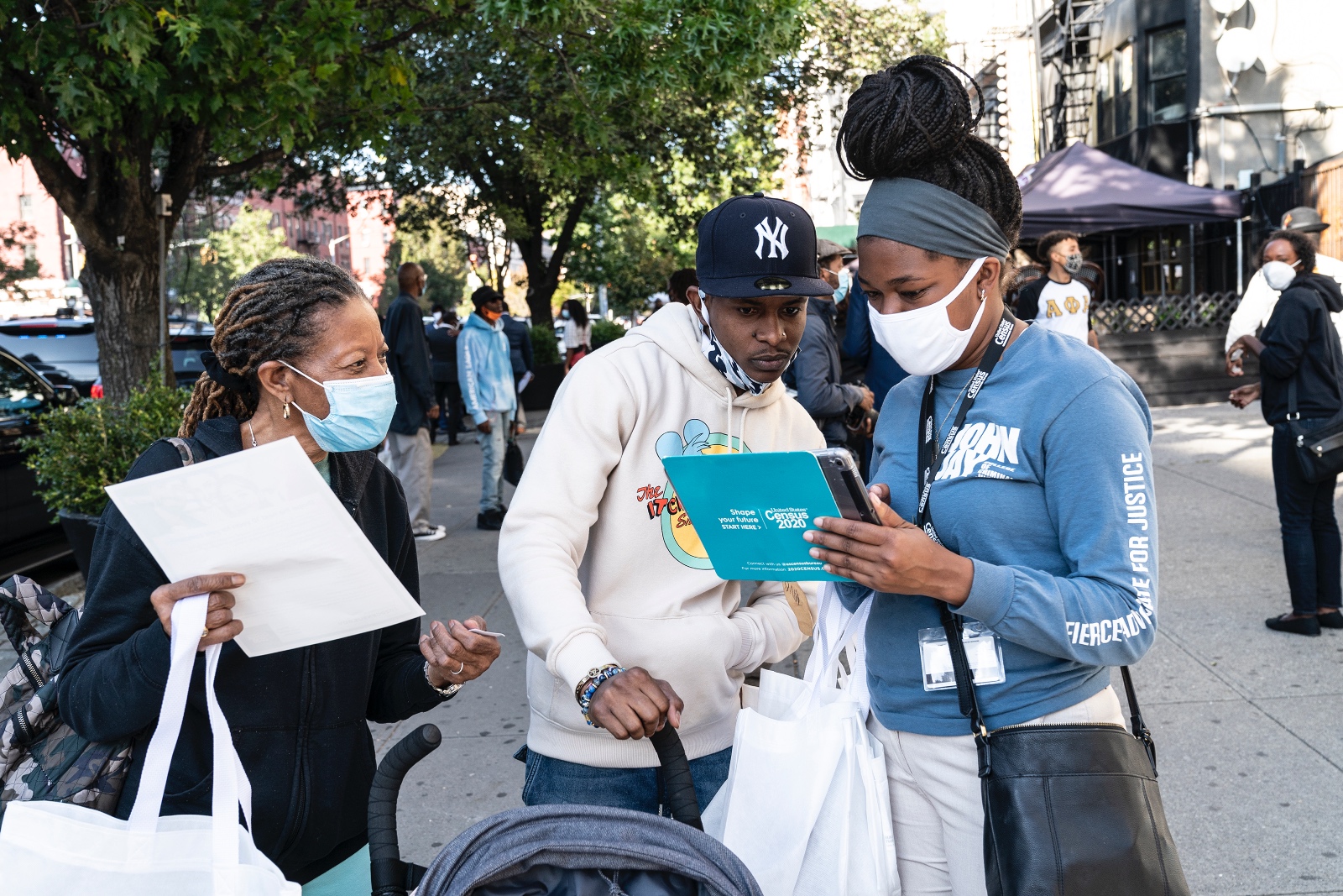 Three people look at a tablet that reads “Census 2020