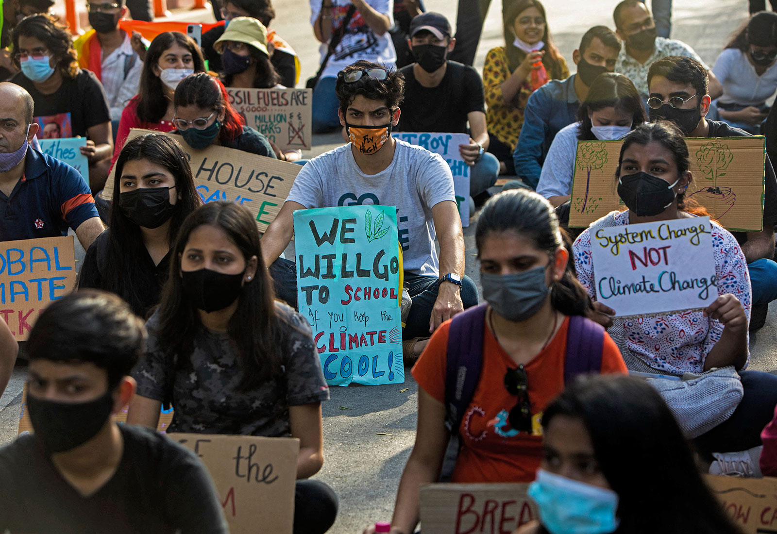 Large group of people in New Delhi sitting holding signs protesting climate change