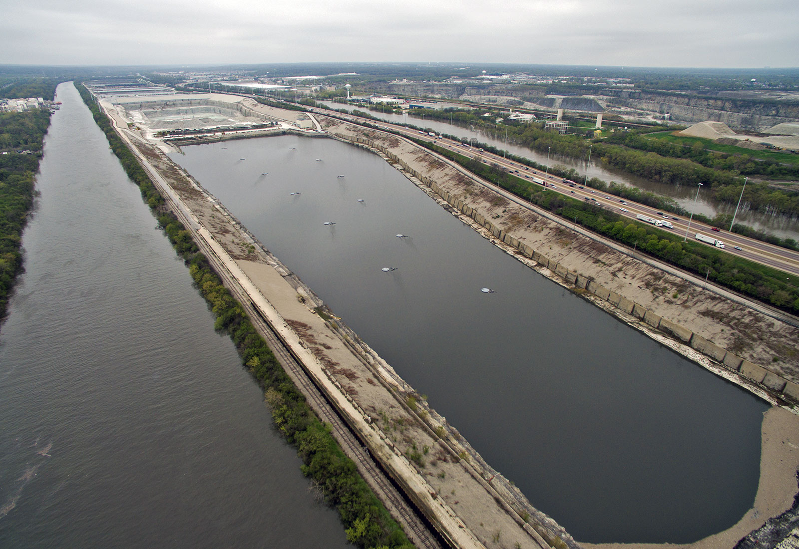 Aerial view of large water reservoir parallel to a river with highways and trees on other side