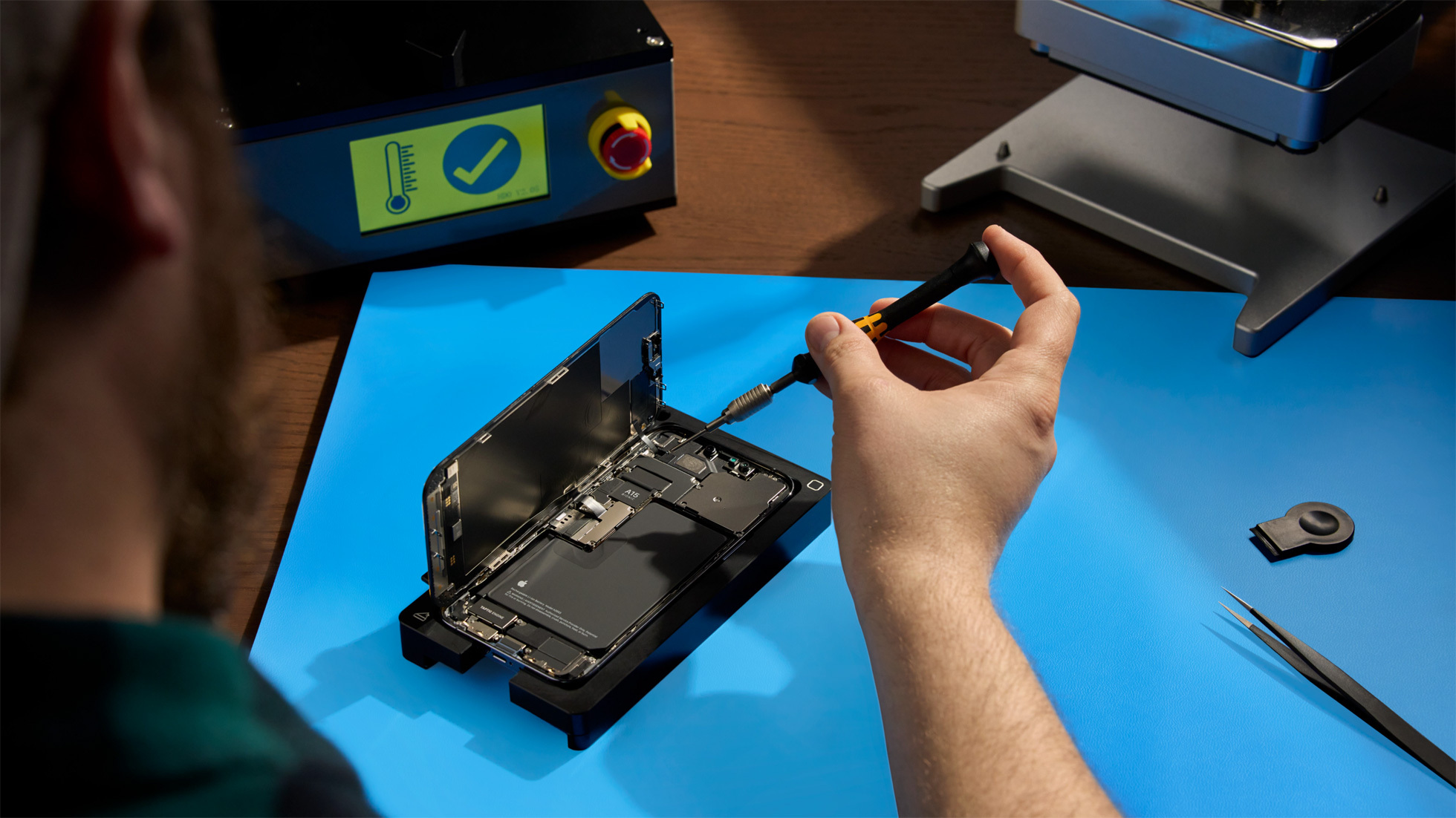 Over the shoulder view of man working on interior of smart phone with small screwdriver