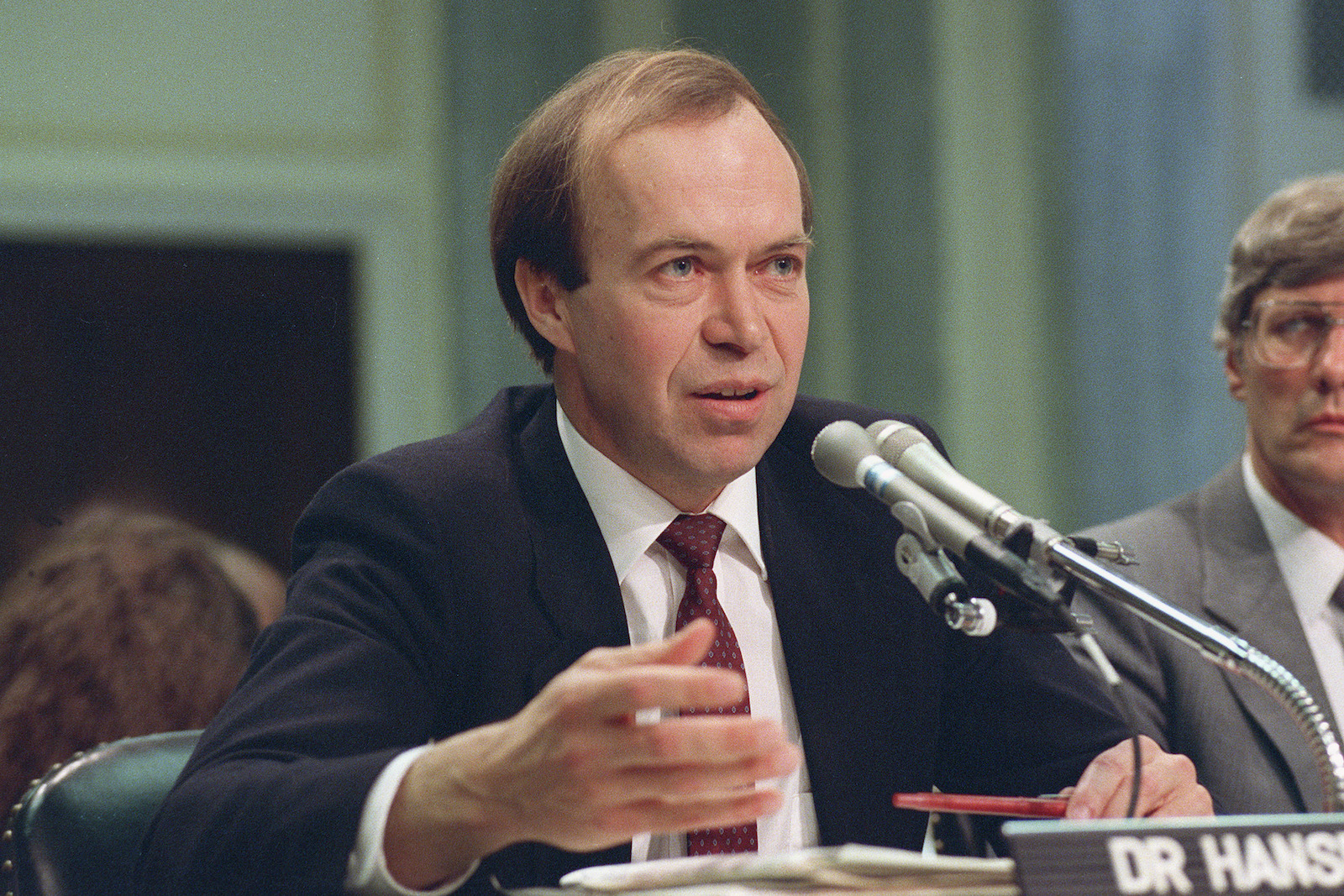 a man in a suit talks in front of a microphone