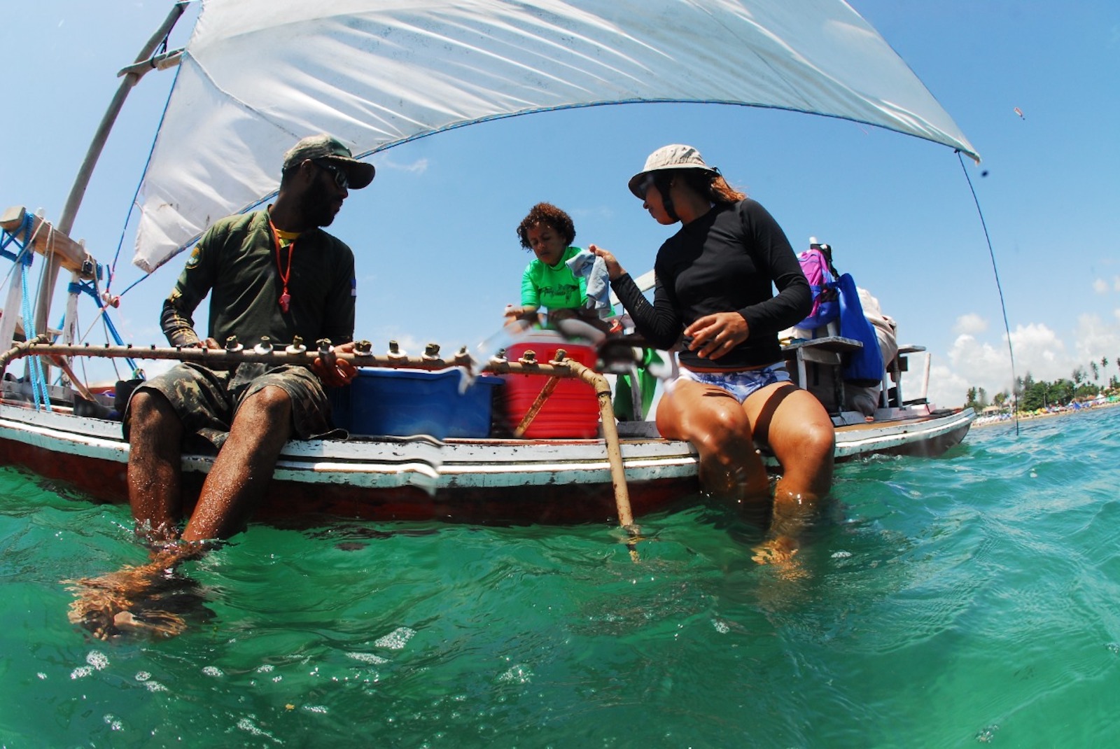 people sit on a boat with their feet in the water.