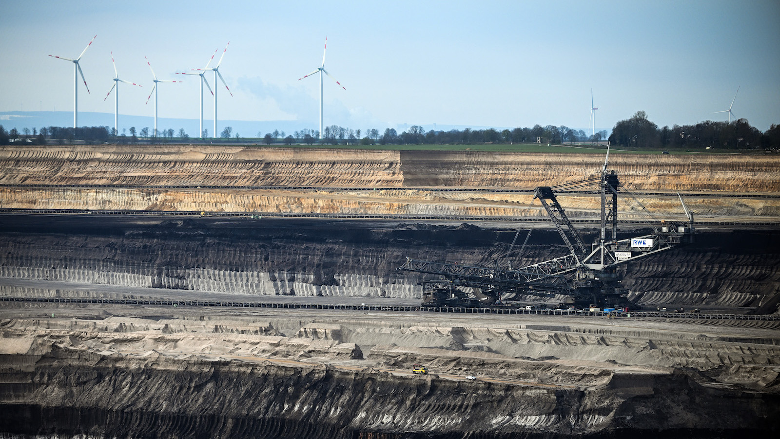 Damage from a mining operation, with wind turbines in background