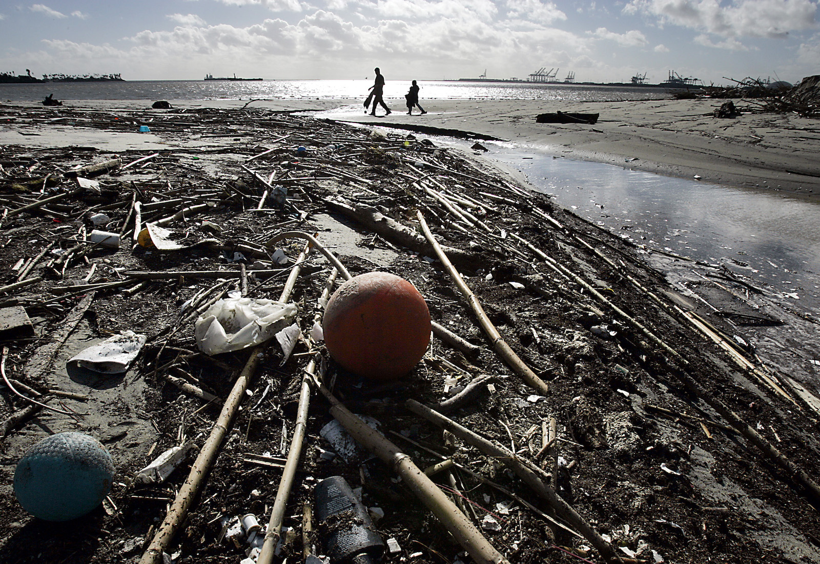 Litter cover a beach with people walking in the distance